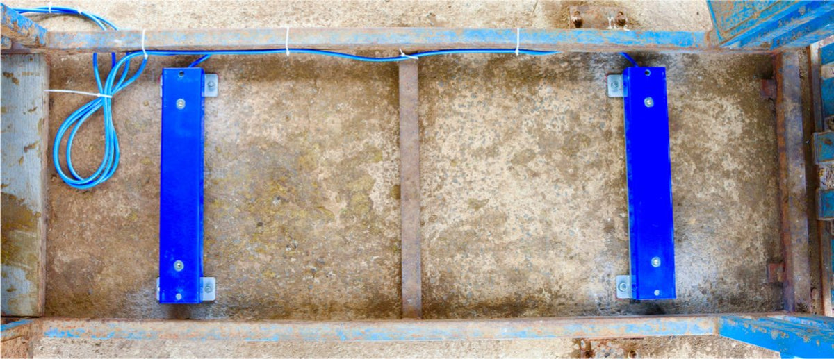 Two load bars fixed to a concrete pad inside a crush with anchor bolts